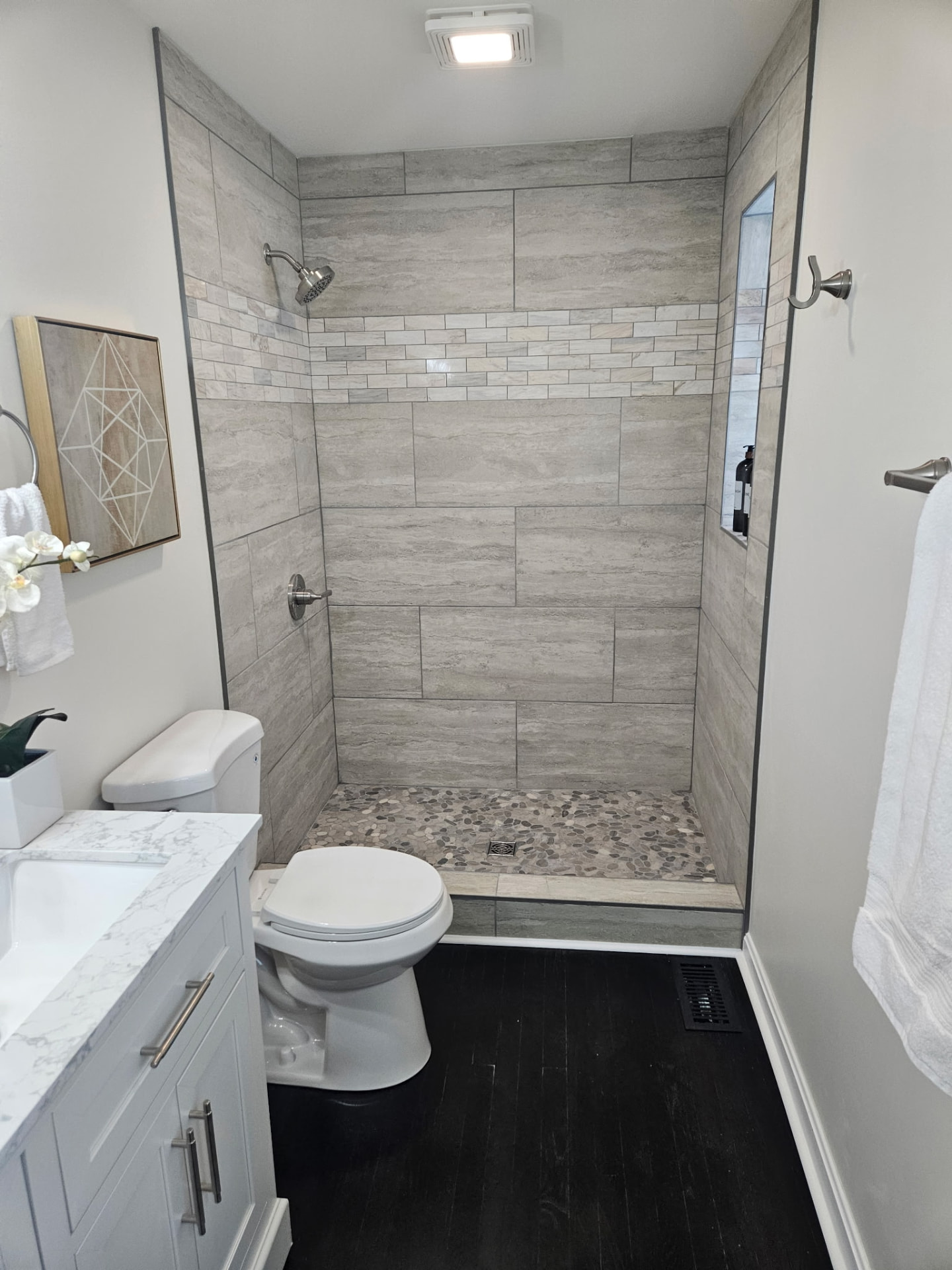 Remodeled bathroom with tiled walk-in shower and pebble floor